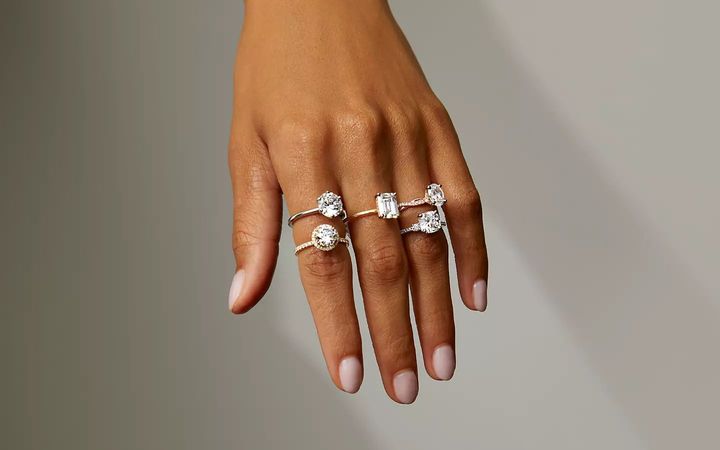 A woman’s hand with multiple rings featuring different setting styles with fancy shaped diamonds